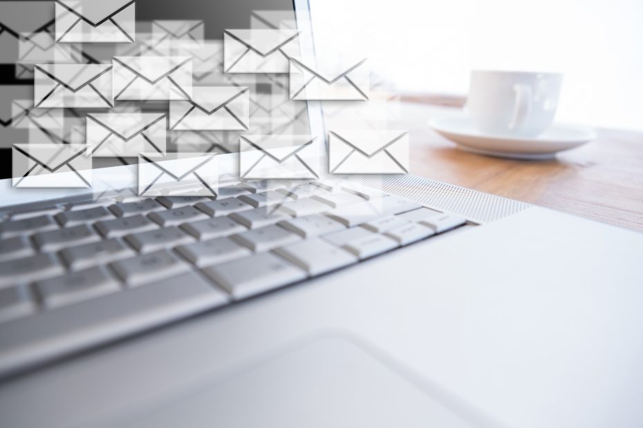 Concept de marketing par e-mail sur un ordinateur portable avec une tasse de café et plein d'icônes d'enveloppes à l'écran.