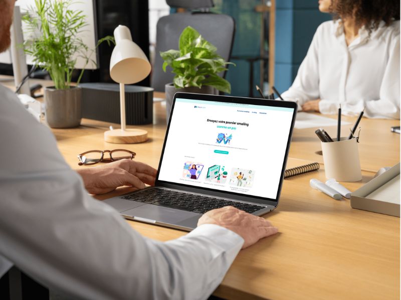 Un homme est assis devant un ordinateur portable, consultant un site web.